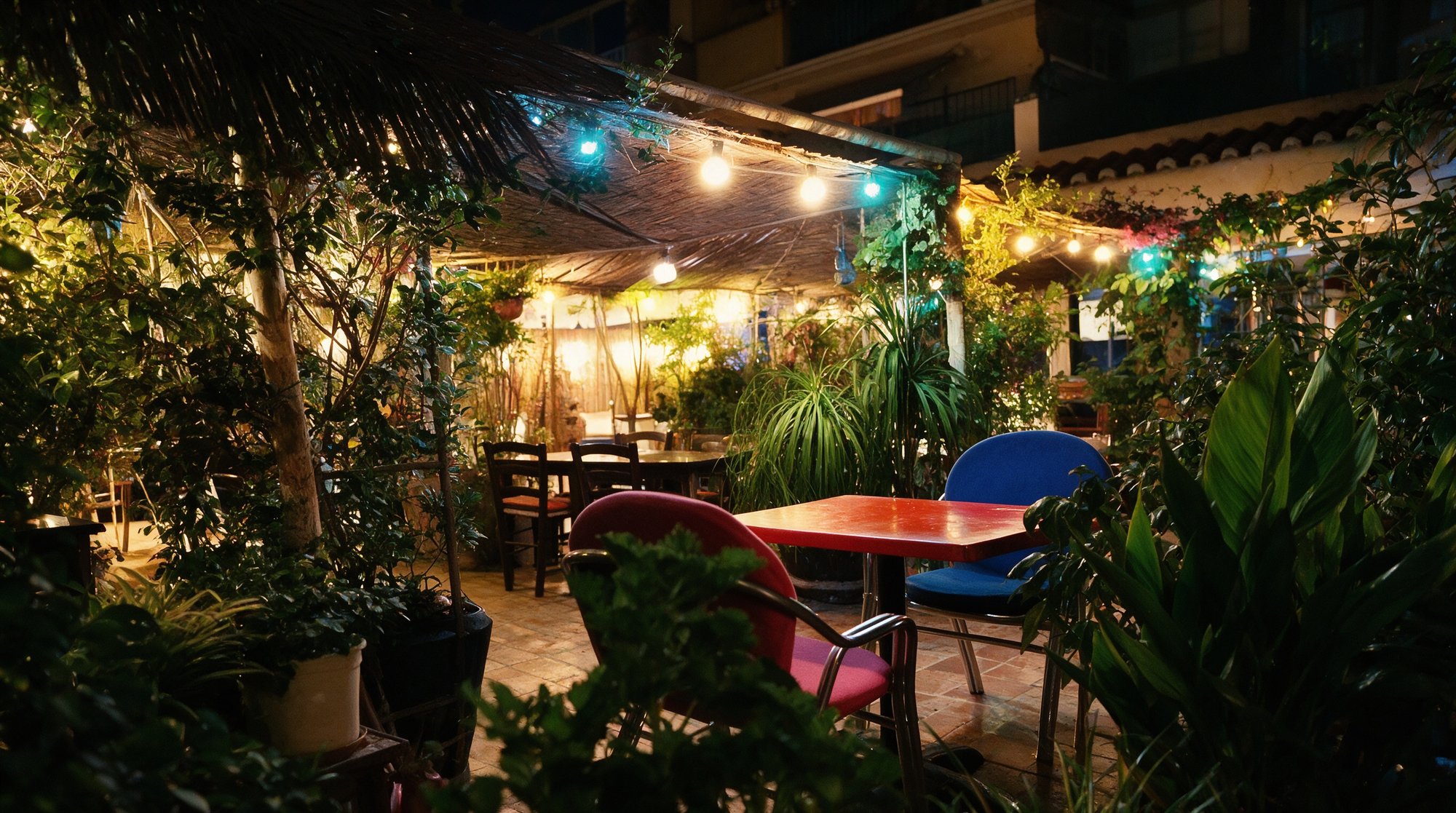 Terraza-jardín nocturna de El Jardín de Tete y Cris en El Morche, mesas entre vegetación bajo luces cálidas